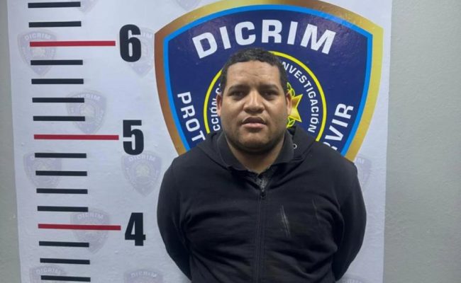 Hombre frente a cartel de DICRIM y estatura