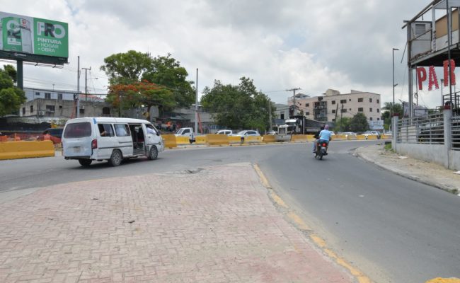 Avenida urbana con tránsito y barricadas amarillas