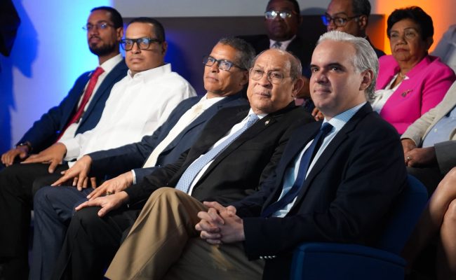 Funcionarios sentados en evento formal bajo luces azules