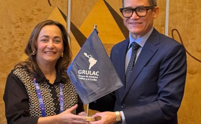 Dos funcionarios sostienen bandera de GRULAC