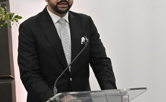 Hombre en traje hablando en podio institucional