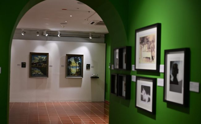 Galería de arte con pinturas en paredes verdes