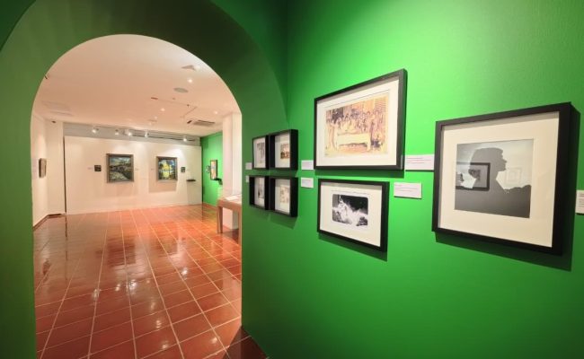 Galería de arte con paredes verdes y cuadros