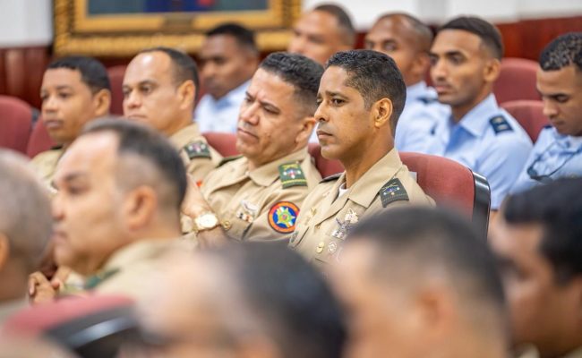 Oficiales militares sentados en auditorio atentos