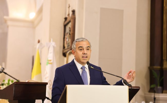 Hombre en traje dando discurso en podio oficial