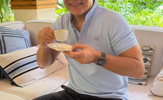 Hombre tomando café en terraza rodeada de plantas