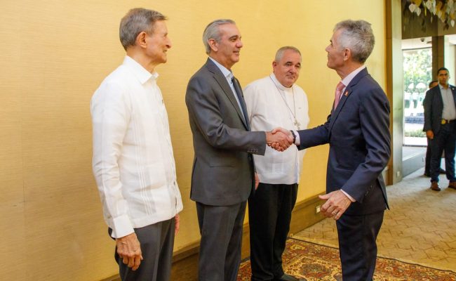 Cuatro hombres en reunión formal estrechando manos