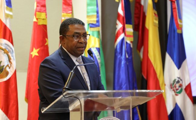 Funcionario hablando en podio con banderas internacionales