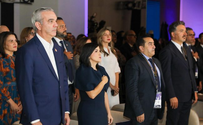 Autoridades en acto oficial con mano en pecho