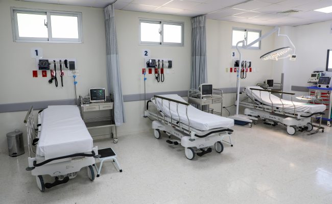 Sala hospitalaria con tres camas y equipos médicos