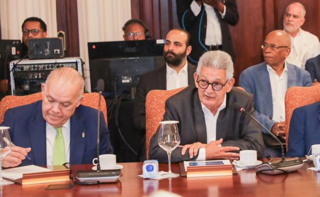 Funcionarios en reunión oficial con micrófonos y documentos