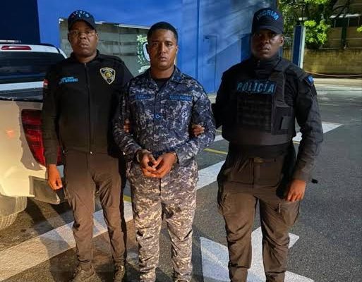 Policías custodian a hombre detenido frente a edificio